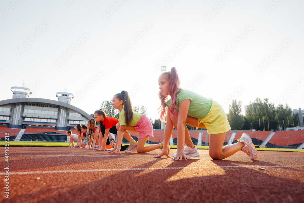 一大群女孩，在开始时就做好了准备，然后在日落时在体育场跑步。健康