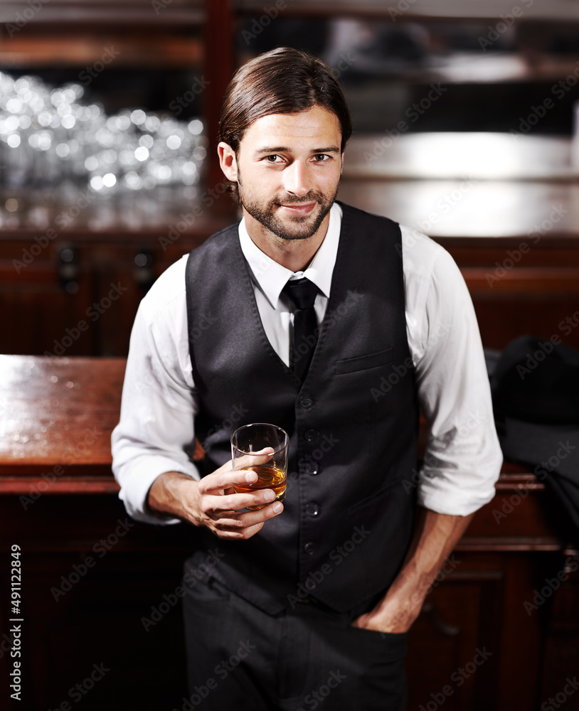 放轻松。一个穿着得体的年轻人坐在酒吧喝酒的画像。