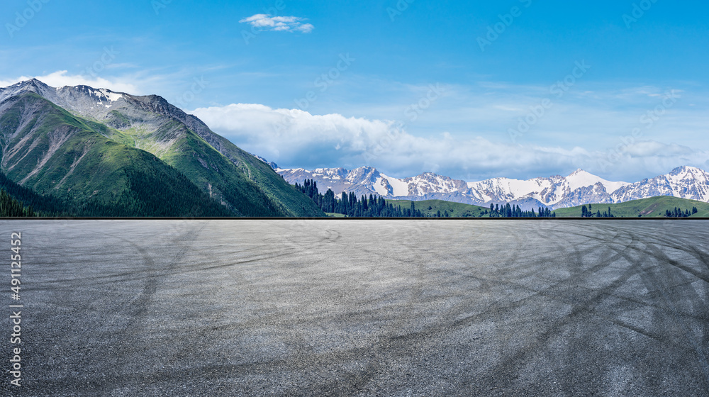 空旷的柏油路和蓝天下的雪山自然风光。道路和山脉的背景。