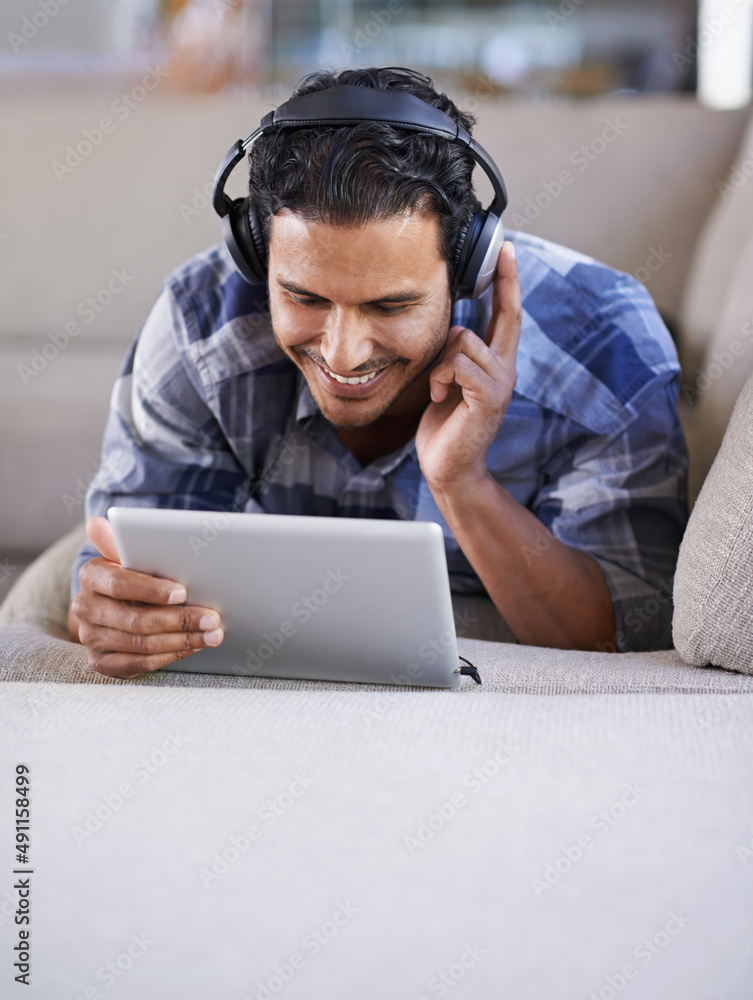 下载他的最爱。一个年轻人在他的数字平板电脑上听音乐。