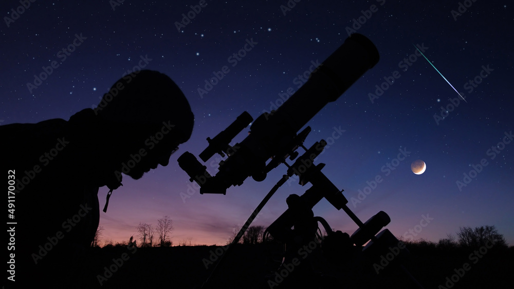傍晚天空下的男人、望远镜和乡村的剪影。