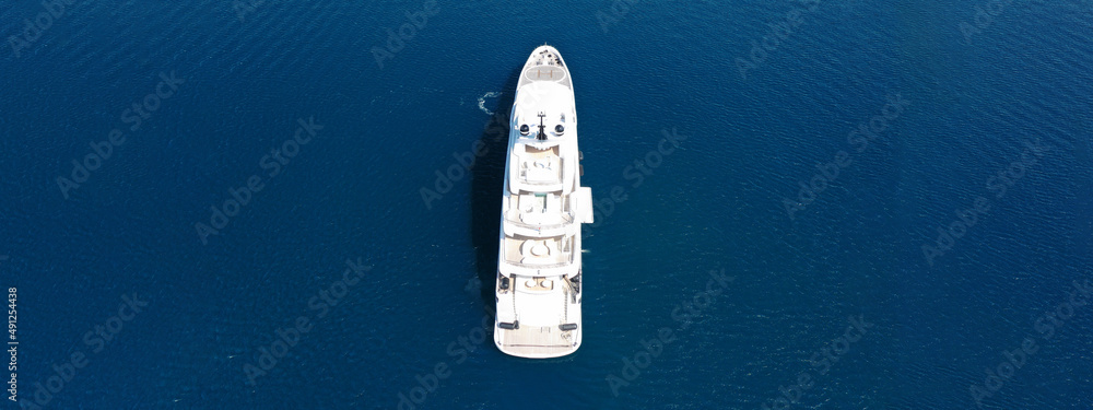 Aerial drone ultra wide top down photo of large yacht with wooden deck anchored in Aegean island dee