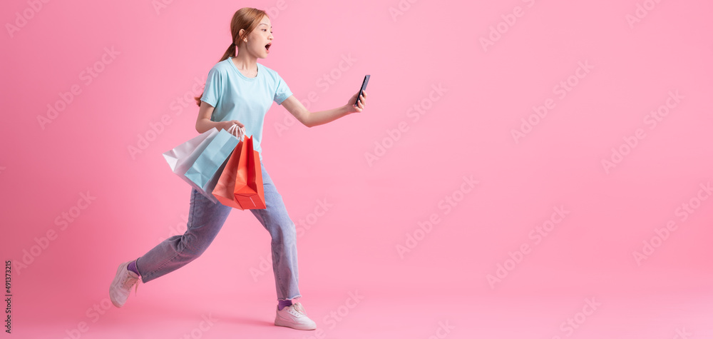 粉红色背景下拿着购物袋的亚洲年轻女子