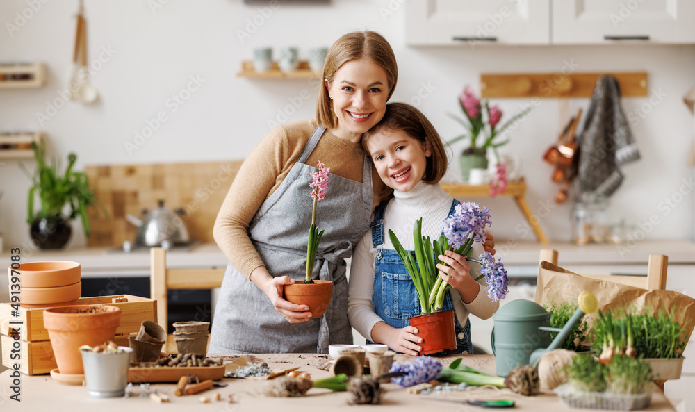 Optimistic mother and daughter with flowers in kitchen