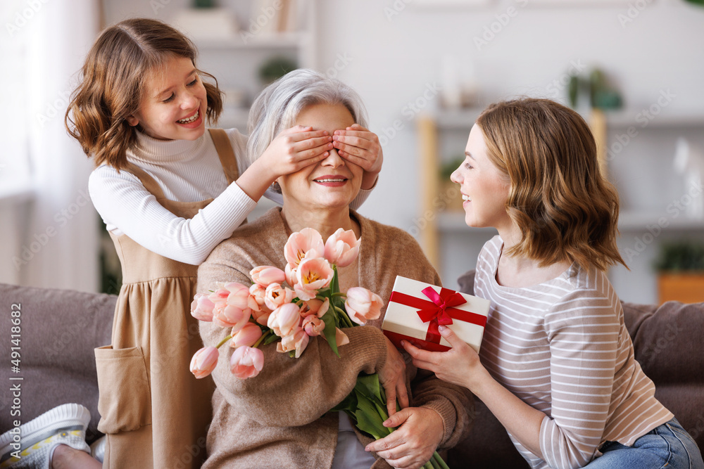 国际母亲节快乐。微笑的女儿和孙女向gra送鲜花和礼物