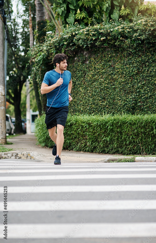 过马路是安全的。拍摄的是一名运动型年轻男子在白天外出锻炼时跑过马路