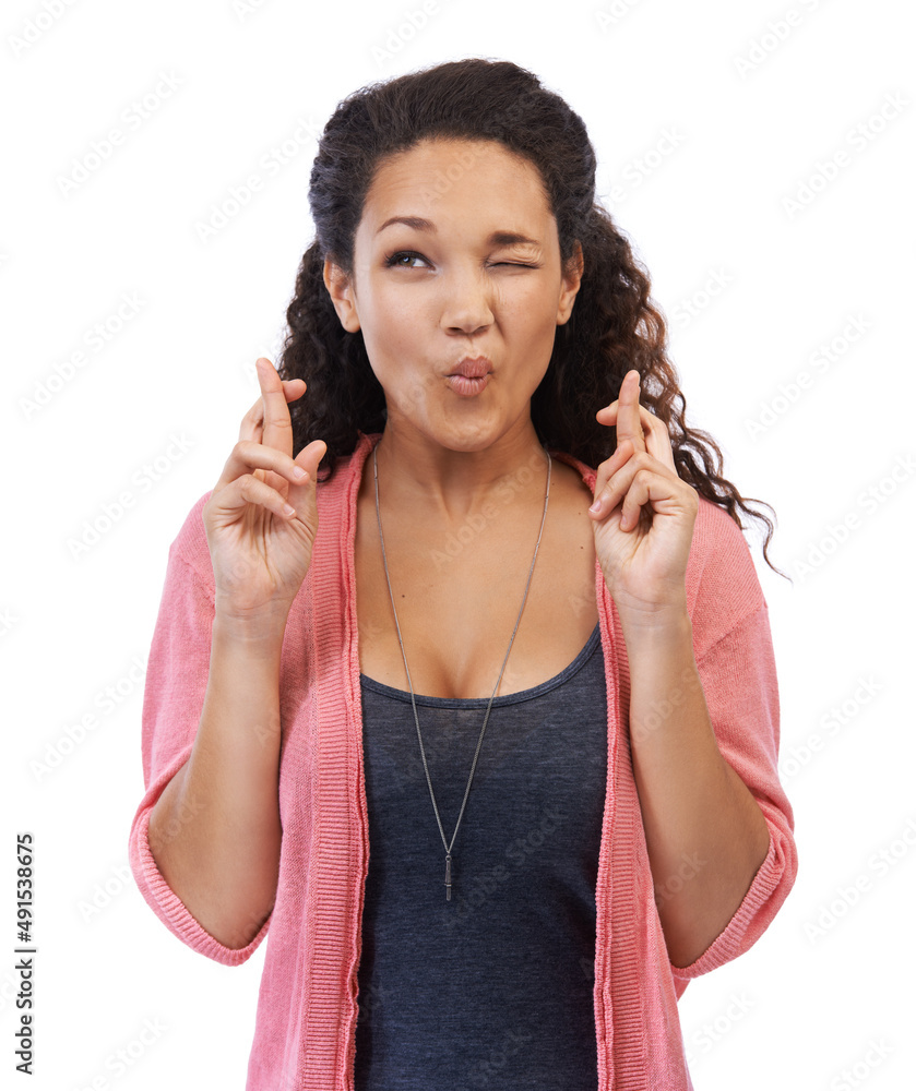Fingers crossed. A beautiful young woman winking with fingers crossed against a white background.