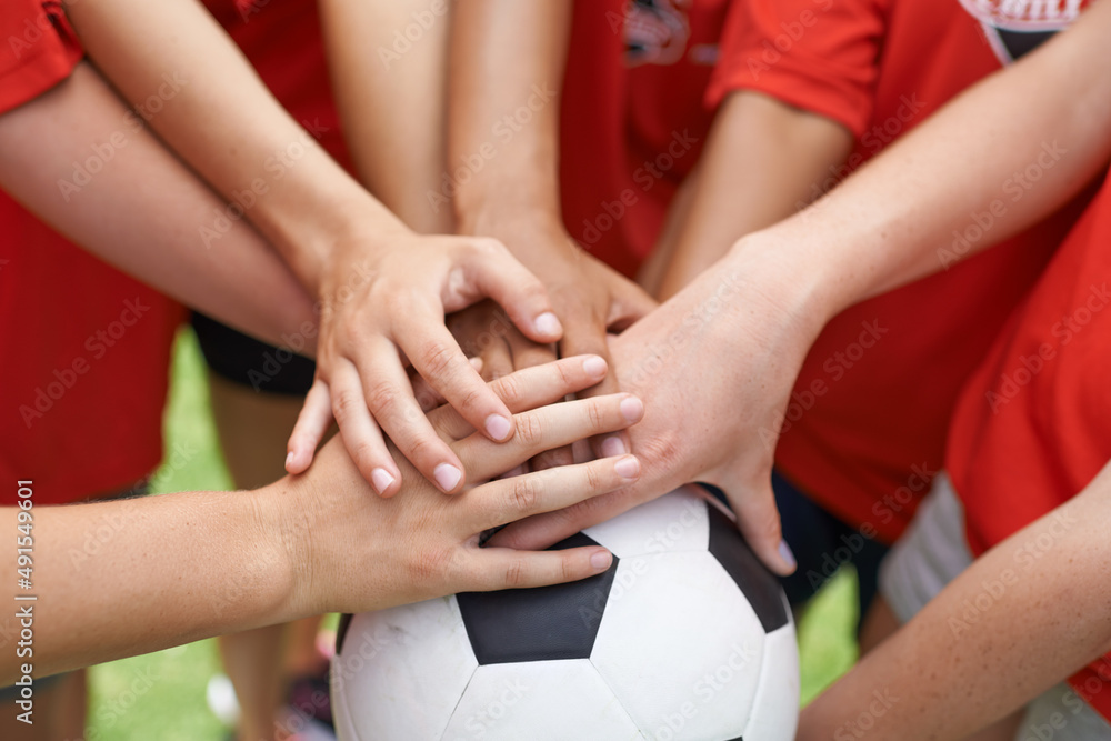 团队精神。一群女孩双手堆在足球上的裁剪图。