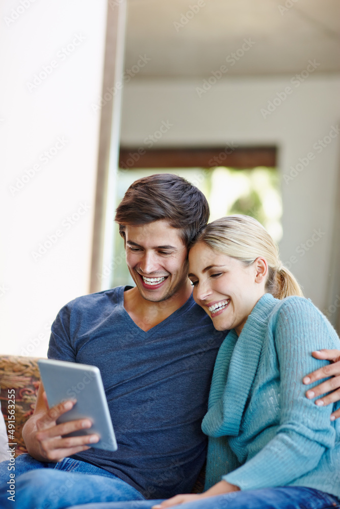 Watching something wacky on the web. Shot of a happy young couple using a digital tablet together on