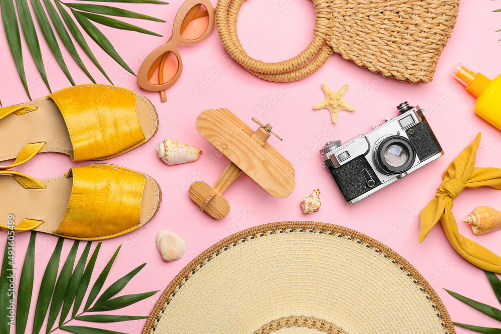 Composition with beach accessories, wooden plane and palm leaves on pink background