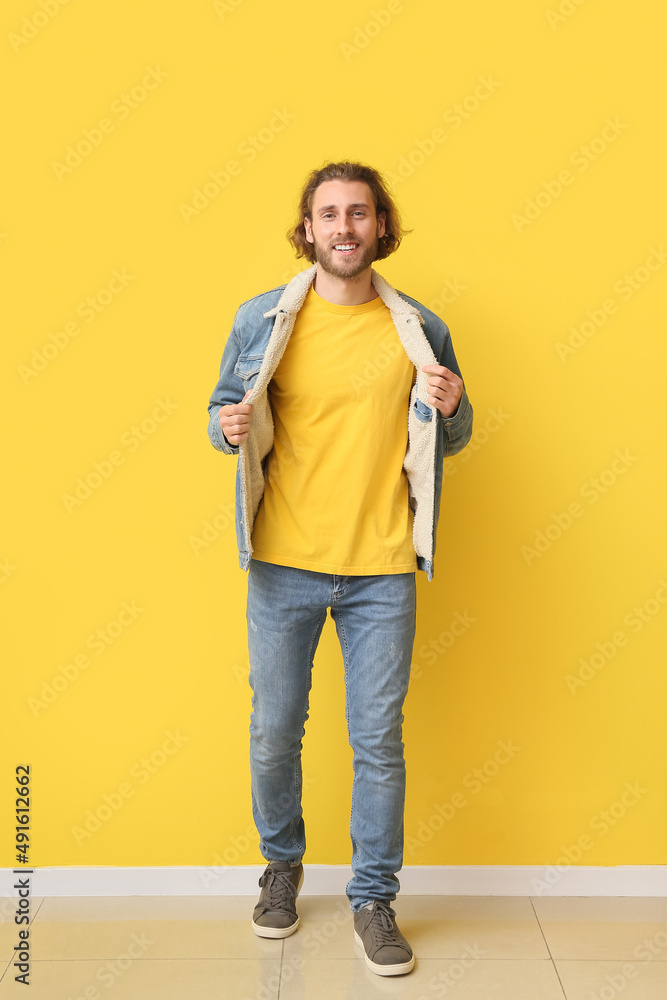帅气的年轻人穿着时尚的t恤和黄色背景的牛仔服