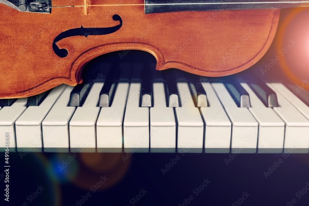 钢琴键盘背景上的小提琴，用于音乐概念