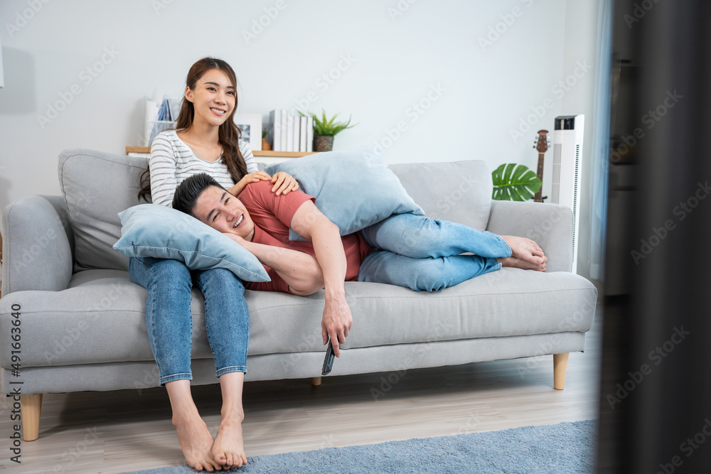 亚洲年轻情侣在家的客厅里一起看电影。