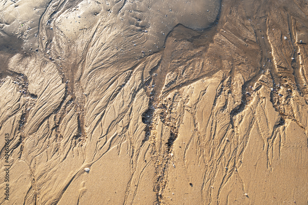 海洋退潮后沙滩上的图案。抽象的沙子自然背景。照片特写