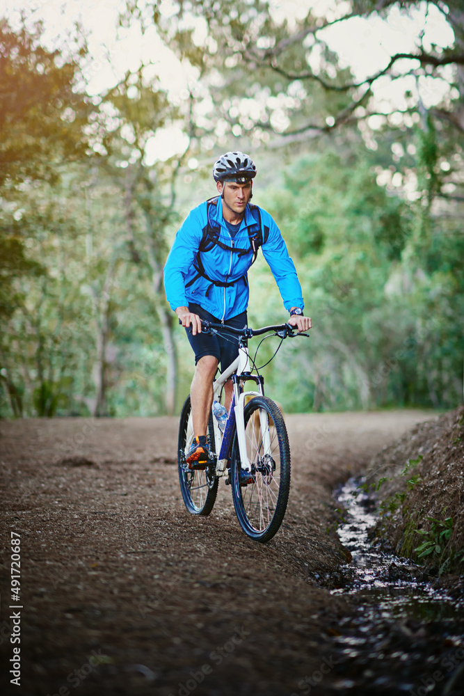 保持健康，享受大自然。一名男性自行车手沿着山地自行车道骑行的照片。