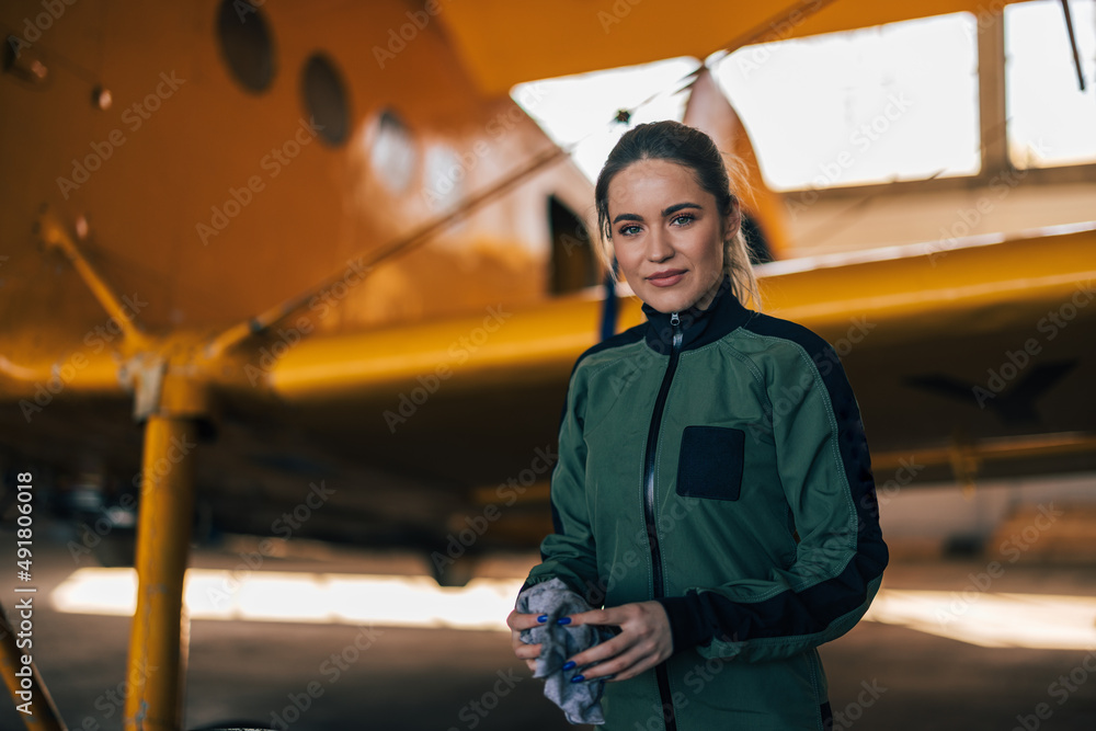 穿着西装的自信女飞行员站在飞机旁边的肖像。