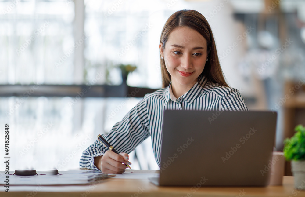 迷人的年轻亚洲商业女性在笔记本电脑办公桌上工作，文件讨论分析d