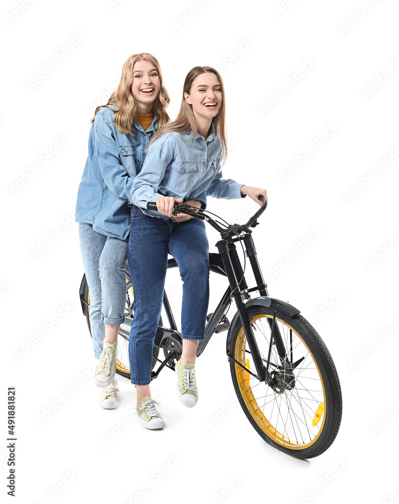 骑着自行车隔离在白色上的快乐年轻姐妹的画像