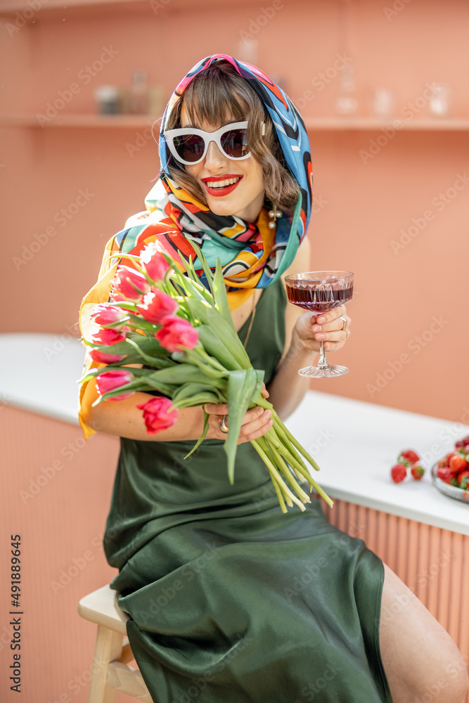 Portrait of a stylish caucasian woman in colorful shawl and sunglasses with flowers and drink celebr