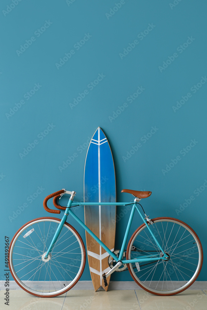 Bicycle and surfboard near color wall in room