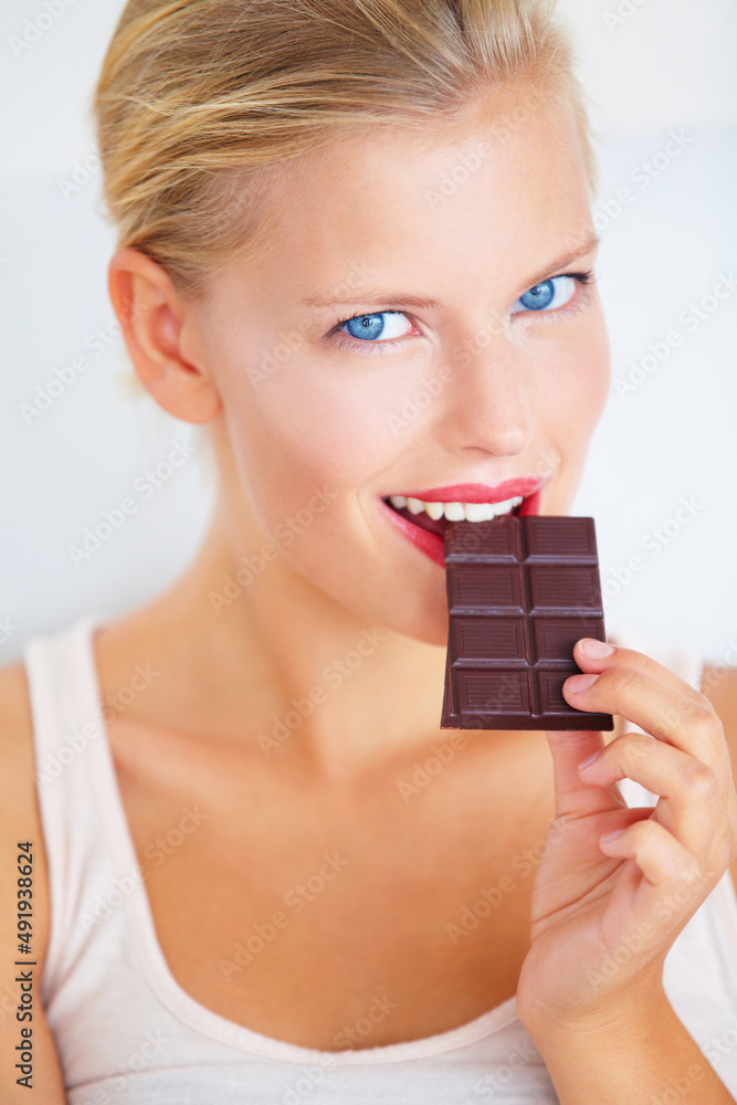 只是一小块……微笑的年轻女子正在享用一块美味的巧克力。