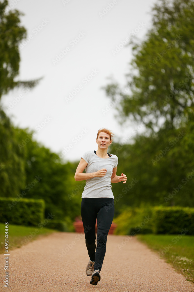 朝着健身目标奔跑。一名女子在公园慢跑的镜头。