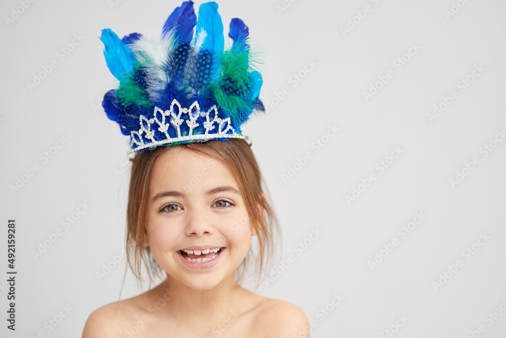 一天的公主。一个可爱的小女孩戴着闪闪发光的羽毛王冠的工作室肖像。