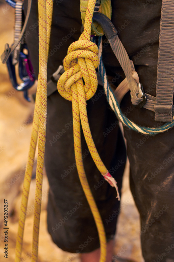 完美的绳结。一个年轻的攀岩者站着调整安全带的裁剪镜头。