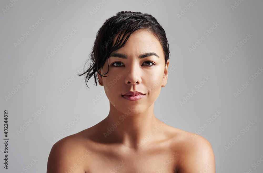 自然无瑕。一位头发湿漉漉的年轻女子在灰色背景下摆姿势的工作室照片。