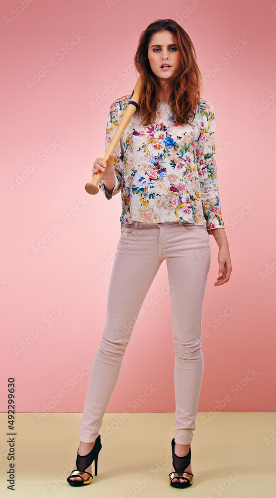 Shes got game. Full length shot of an attractive young woman holding a baseball bat against a pink b