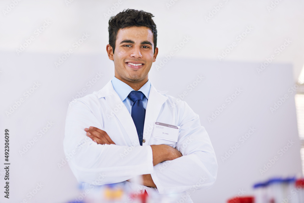科学是它自己的满足。一个微笑的实验室技术人员站在实验室里的画像。