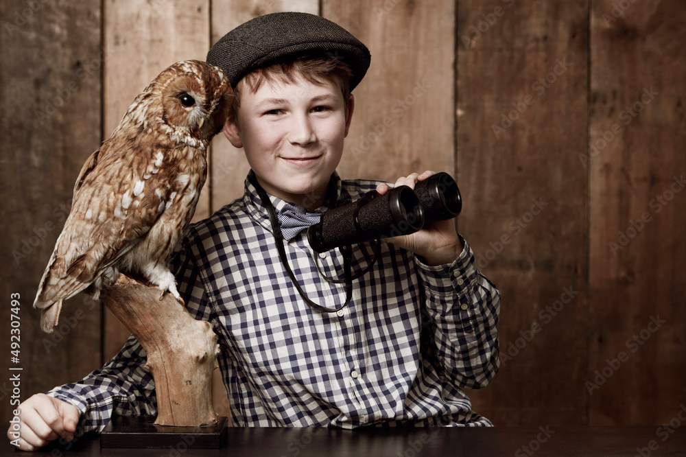 鸟类学太有趣了。一个穿着复古衣服、戴着眼镜、手持双筒望远镜的小男孩