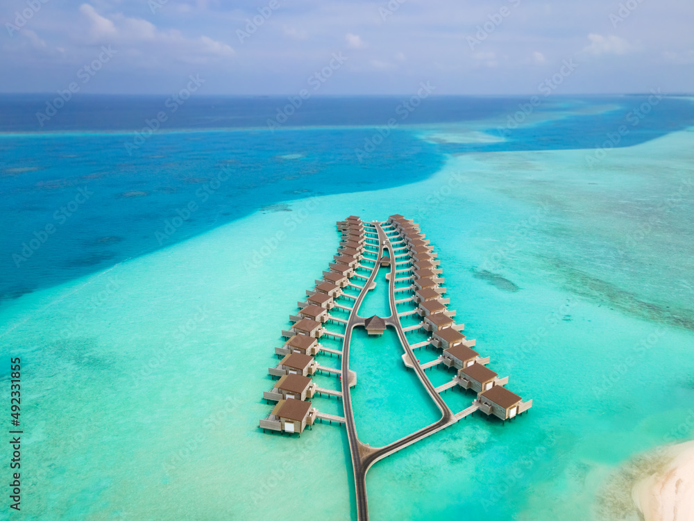 热带岛屿上的水上别墅和白色沙滩，用于度假旅行和蜜月。