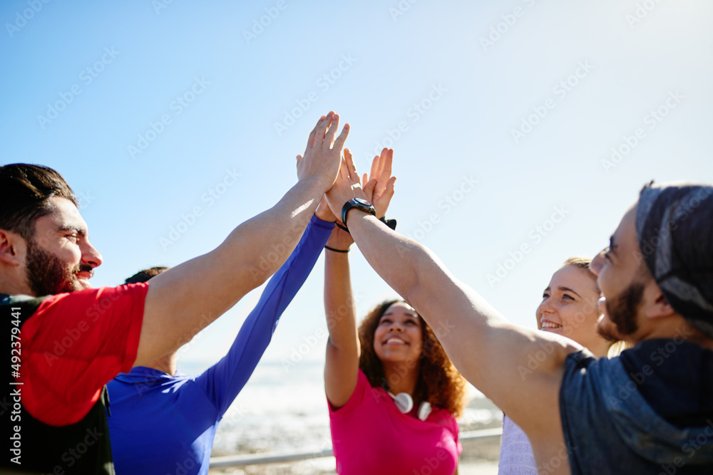 Put them up high. Shot of a group of young cheerful friends giving high fives before a fitness exerc