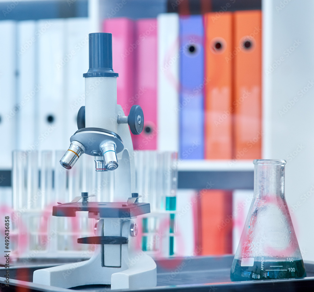 每一个实验都能促进发现和学习。实验室中显微镜和烧杯的特写镜头。