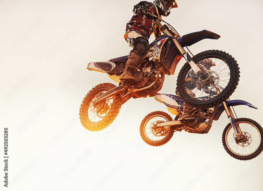 他们并驾齐驱。比赛中两名越野摩托车手在半空中的镜头。