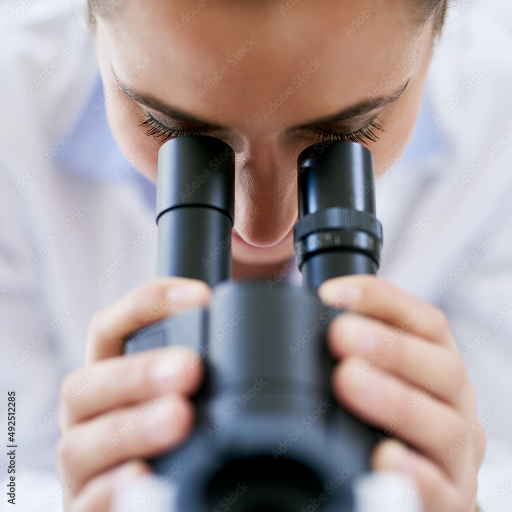 推进医学科学。一位年轻女科学家在实验室使用显微镜的裁剪镜头。