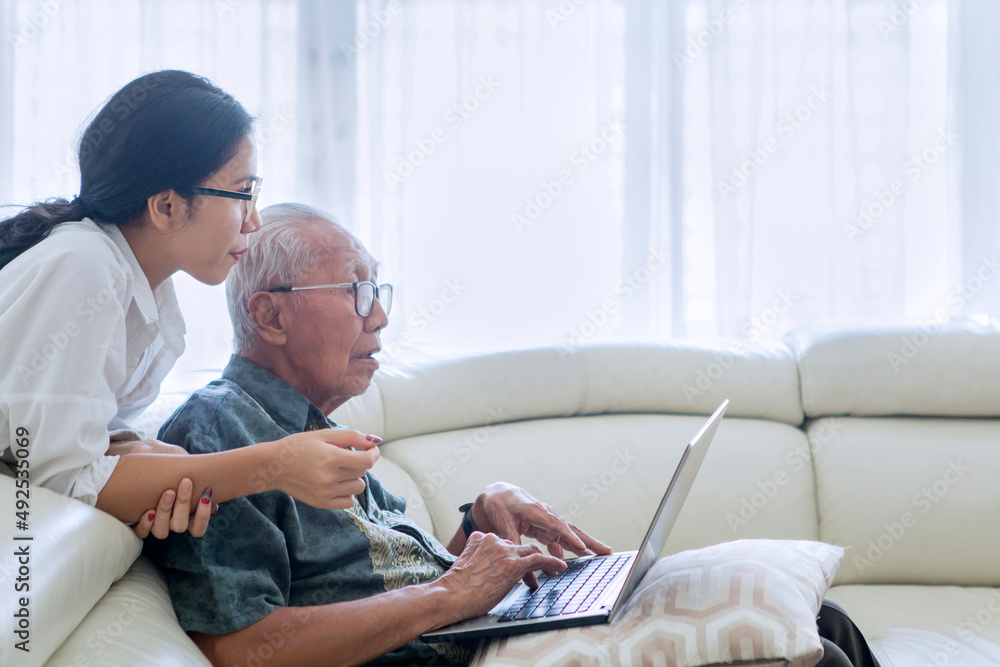 Senior man using laptop with his daughter at home