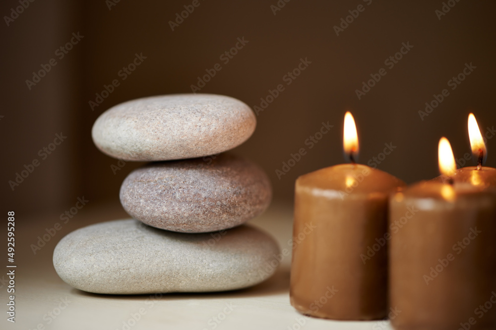 自然疗法。三块石头相互平衡，旁边放着一些蜡烛。