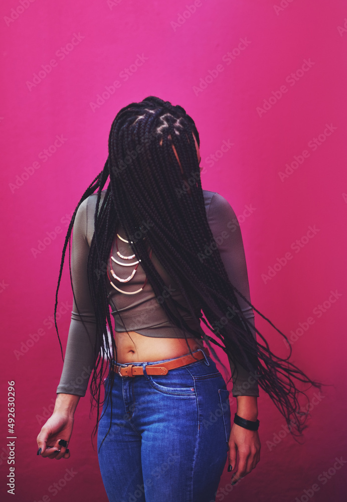生命太短，不会有无聊的头发。一个扎着辫子的年轻女人靠着粉色的臀部摆姿势的照片
