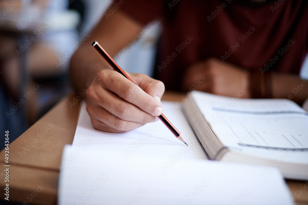 养成良好的学习习惯。一个年轻学生在笔记本上写字的特写镜头。