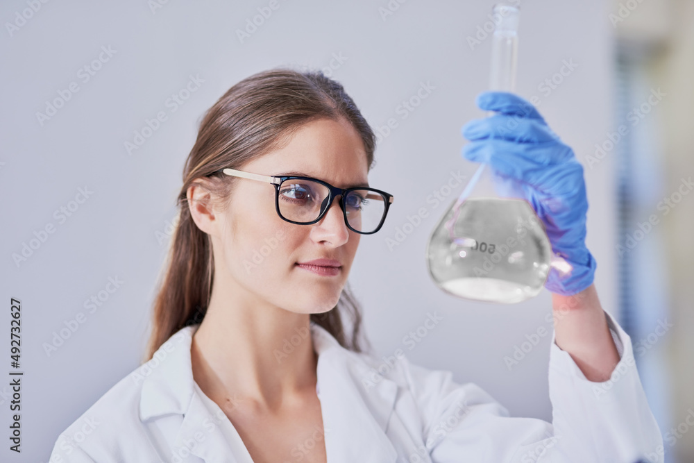 新发现。一名科学家站在实验室里检查一烧杯液体的照片