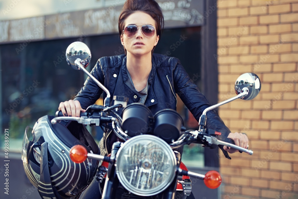 摩托车风格。拍摄的是一位年轻时尚的女摩托车手在外面。