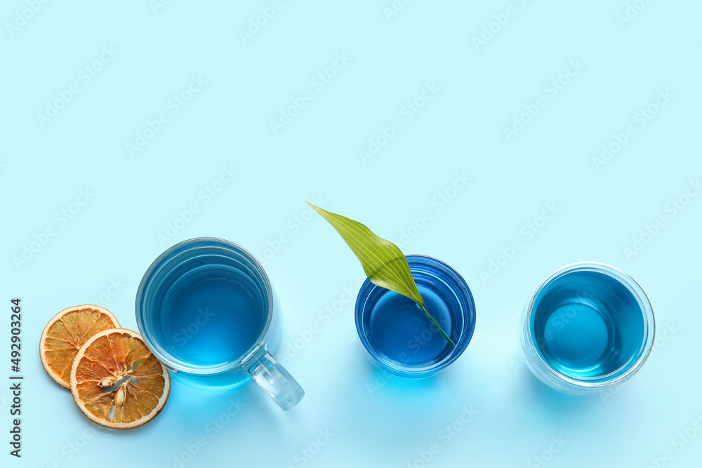 彩色背景上的几杯蓝茶和干橙