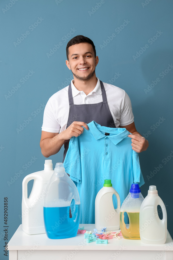 蓝色背景下穿着t恤、桌子、衣服和洗衣粉的年轻人