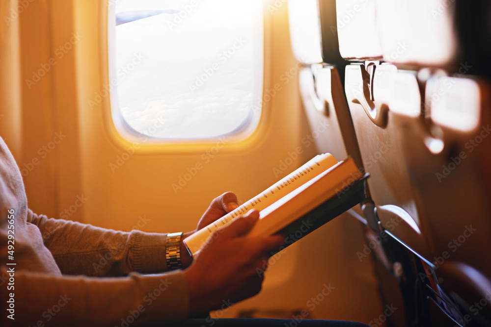 阅读是你想象飞行的一种方式。一名乘客在空中看书的照片