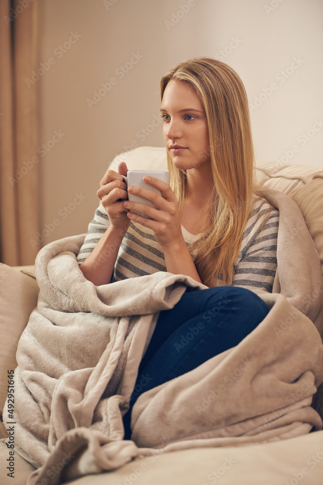 Relaxing with a cup of java. Shot of an attractive young woman drinking a coffee at home.