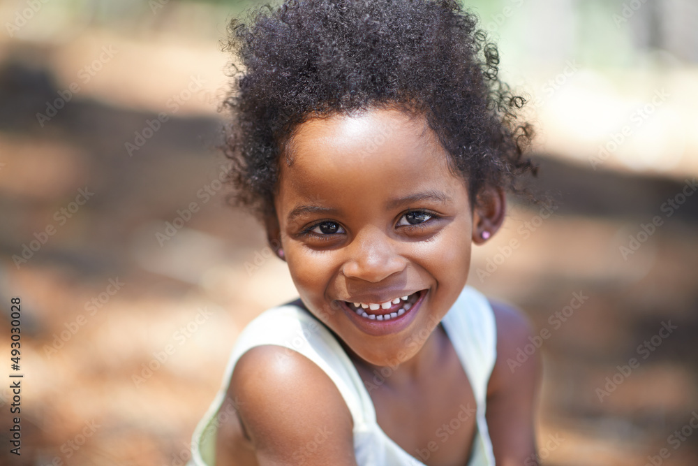 她喜欢在树林里玩耍。一个可爱的小女孩在享受时对着镜头微笑的肖像