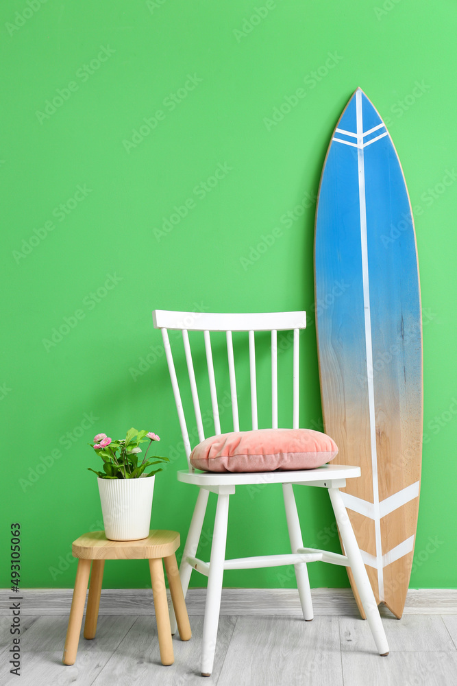 房间彩色墙附近的带室内植物、椅子和冲浪板的凳子