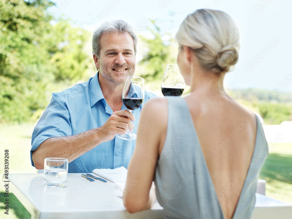享受午餐约会。快乐的成熟情侣在户外用两杯葡萄酒为他们的爱情干杯